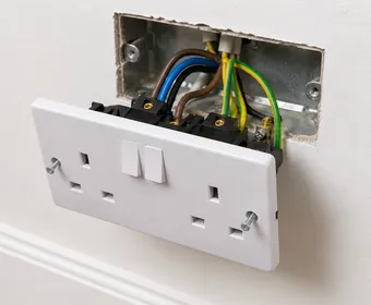 A close-up of a newly wired double socket being fitted into a wall